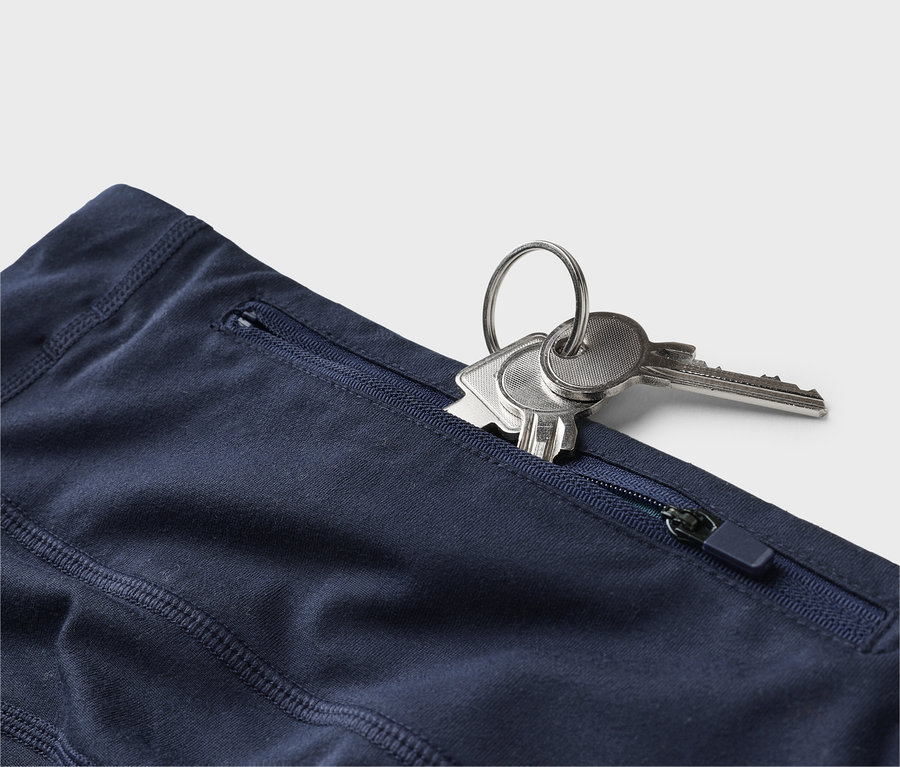Gros plan d'un pantalon bleu marine avec des clés dans une poche zippée.