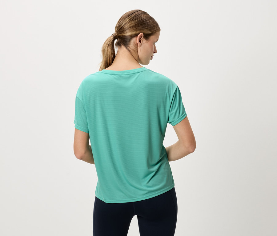 Vue arrière d'une femme avec une queue de cheval portant un haut de sport turquoise et un legging bleu marine.