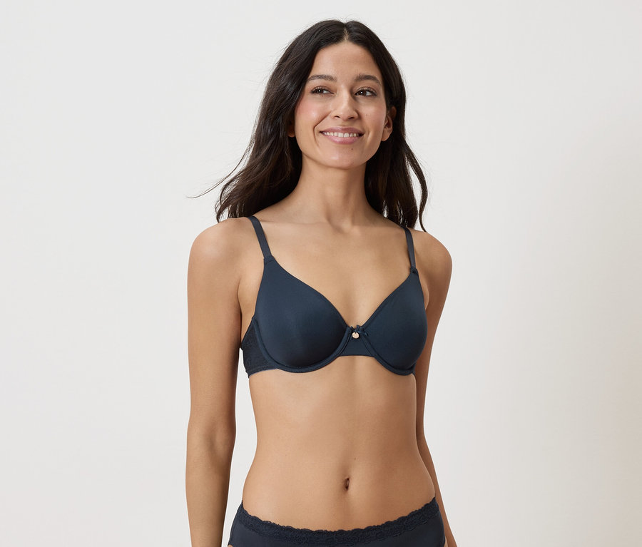 Femme portant un soutien-gorge et des sous-vêtements bleu marine sur fond blanc.