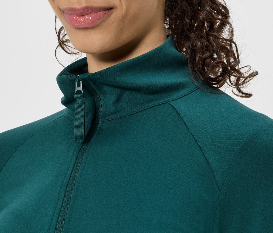 Gros plan d'une femme portant une veste verte zippée à col montant.