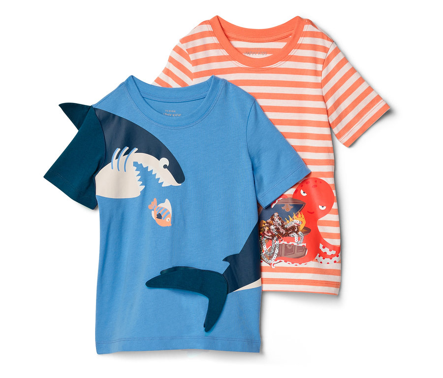 Deux T-shirts pour enfants sont côte à côte : un bleu avec un motif de requin et un rayé orange et blanc avec une pieuvre et un coffre au trésor.