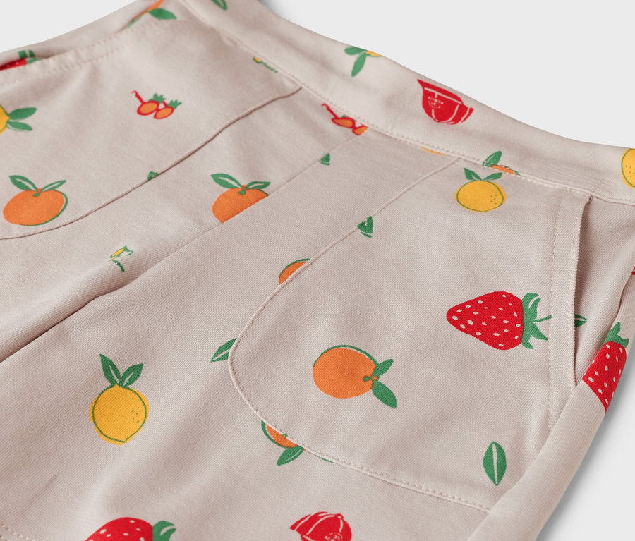 Gros plan d'un pantalon beige avec un motif de fruits.