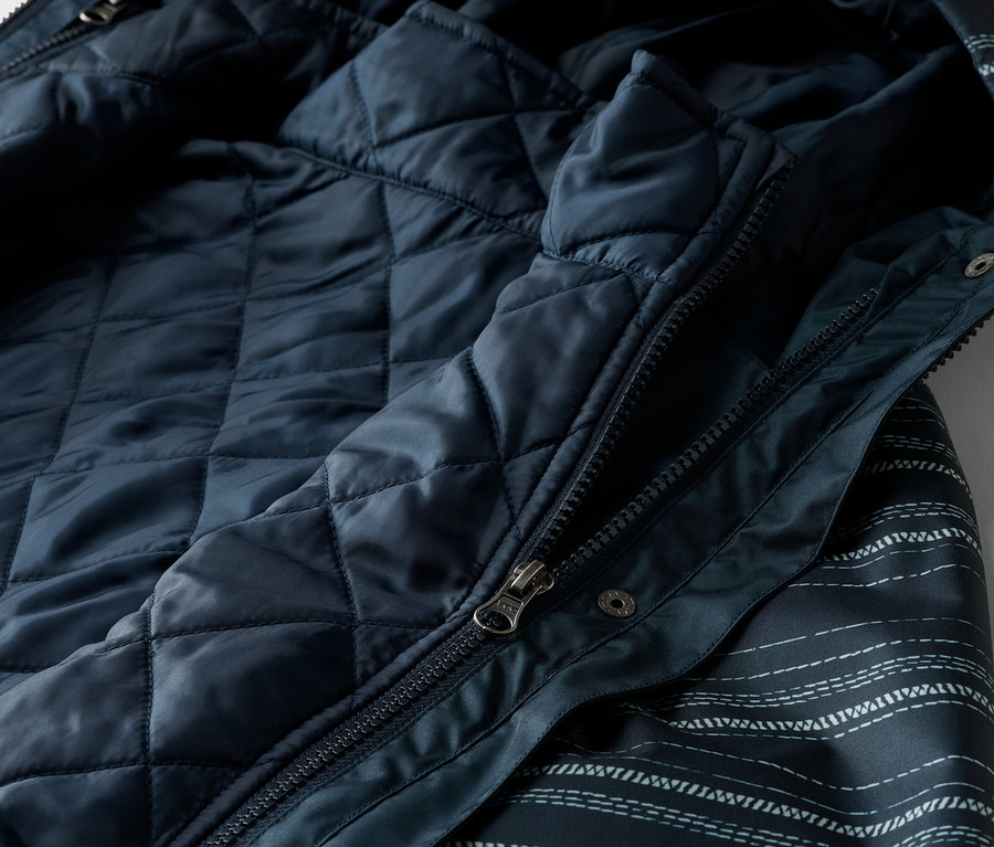 Gros plan d'une veste bleu marine avec fermeture éclair et doublure matelassée.