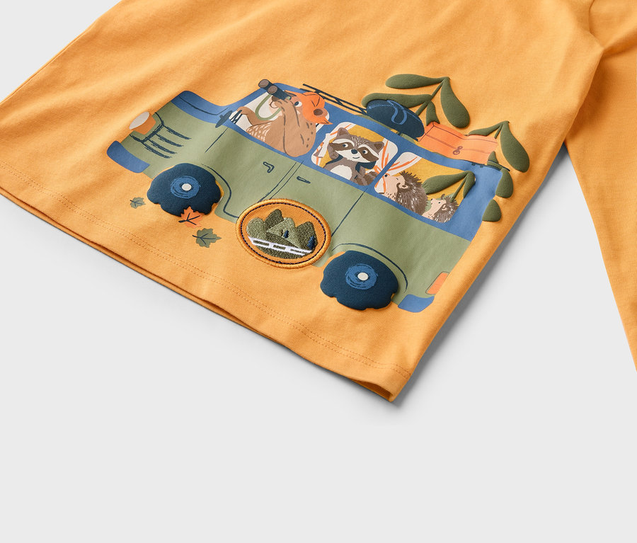 Sur un tissu orange est imprimée une voiture verte avec des animaux, dont un cerf, un raton laveur et un hérisson.