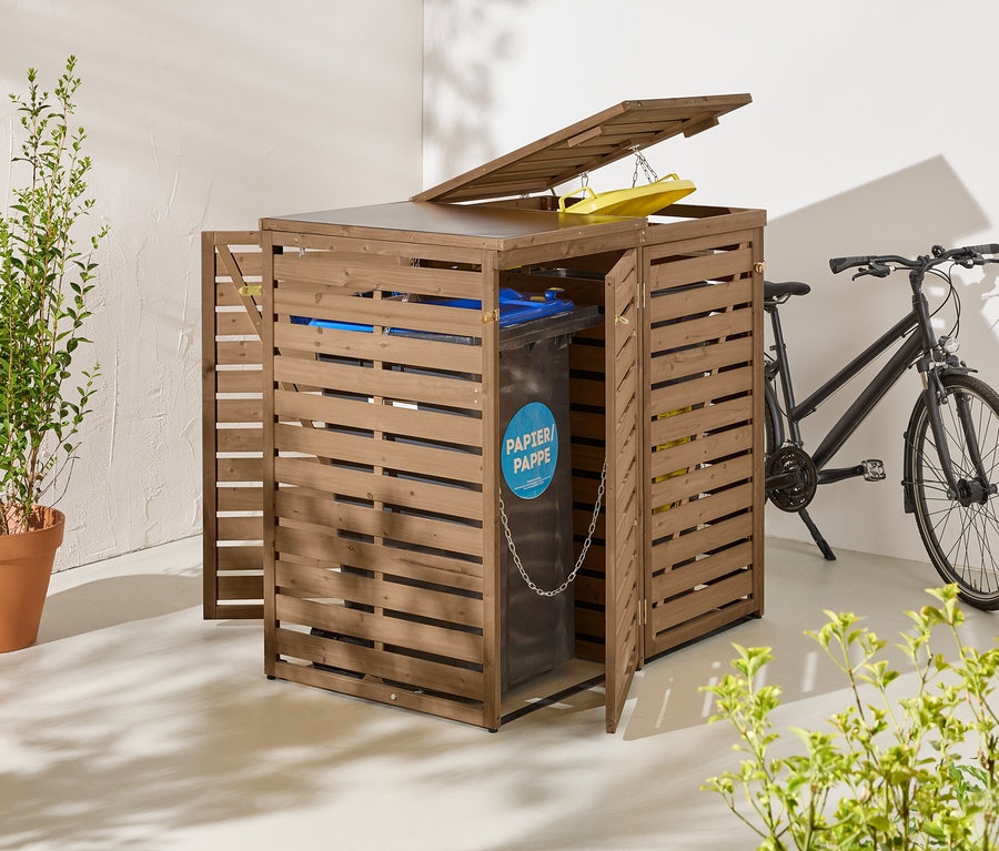 Un coffre à poubelles en bois marron avec portes et couvercle ouverts se trouve à côté d'un vélo noir.