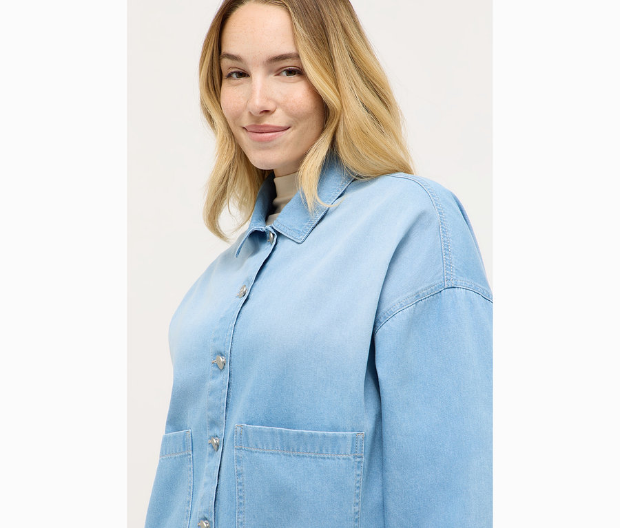 Femme portant une chemise en jean bleu clair.