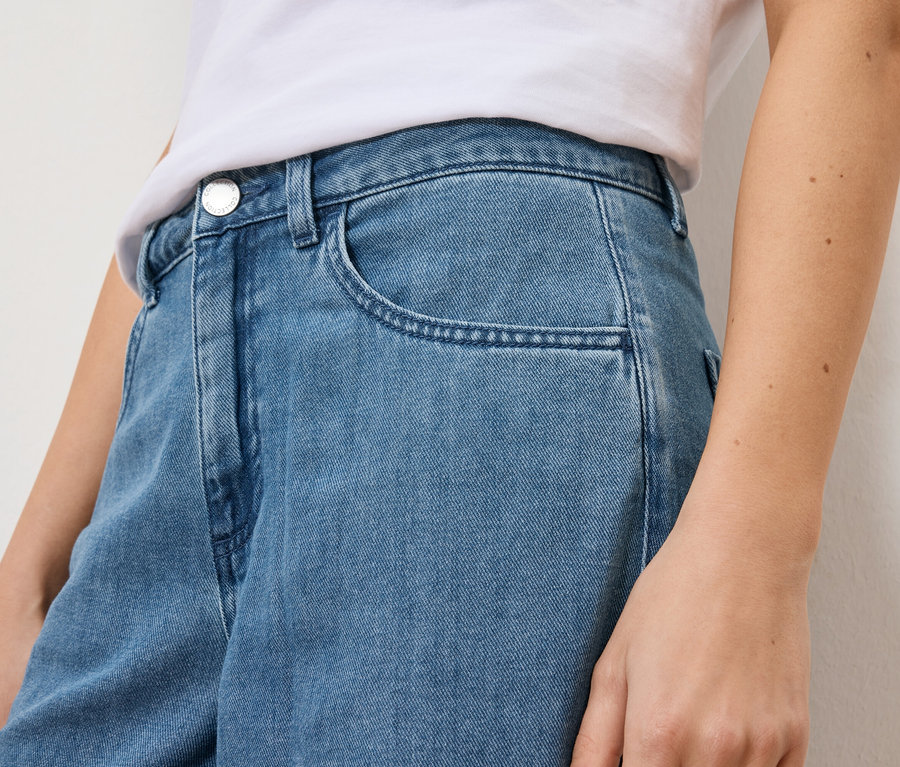 Gros plan d'une femme portant un jean bleu clair et un t-shirt blanc.