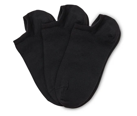 Trois chaussettes courtes noires sont posées les unes sur les autres sur un fond blanc.