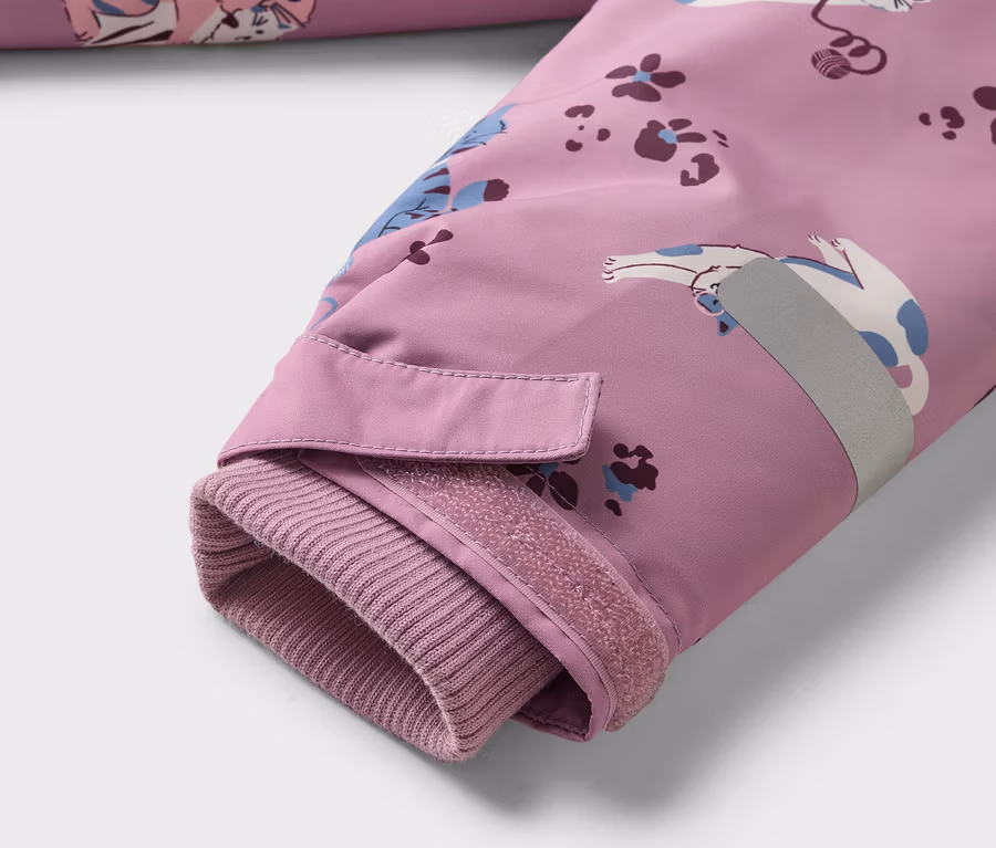 Gros plan sur la manche d'une veste violette à motif de chat, avec poignet côtelé, fermeture velcro et bande réfléchissante.