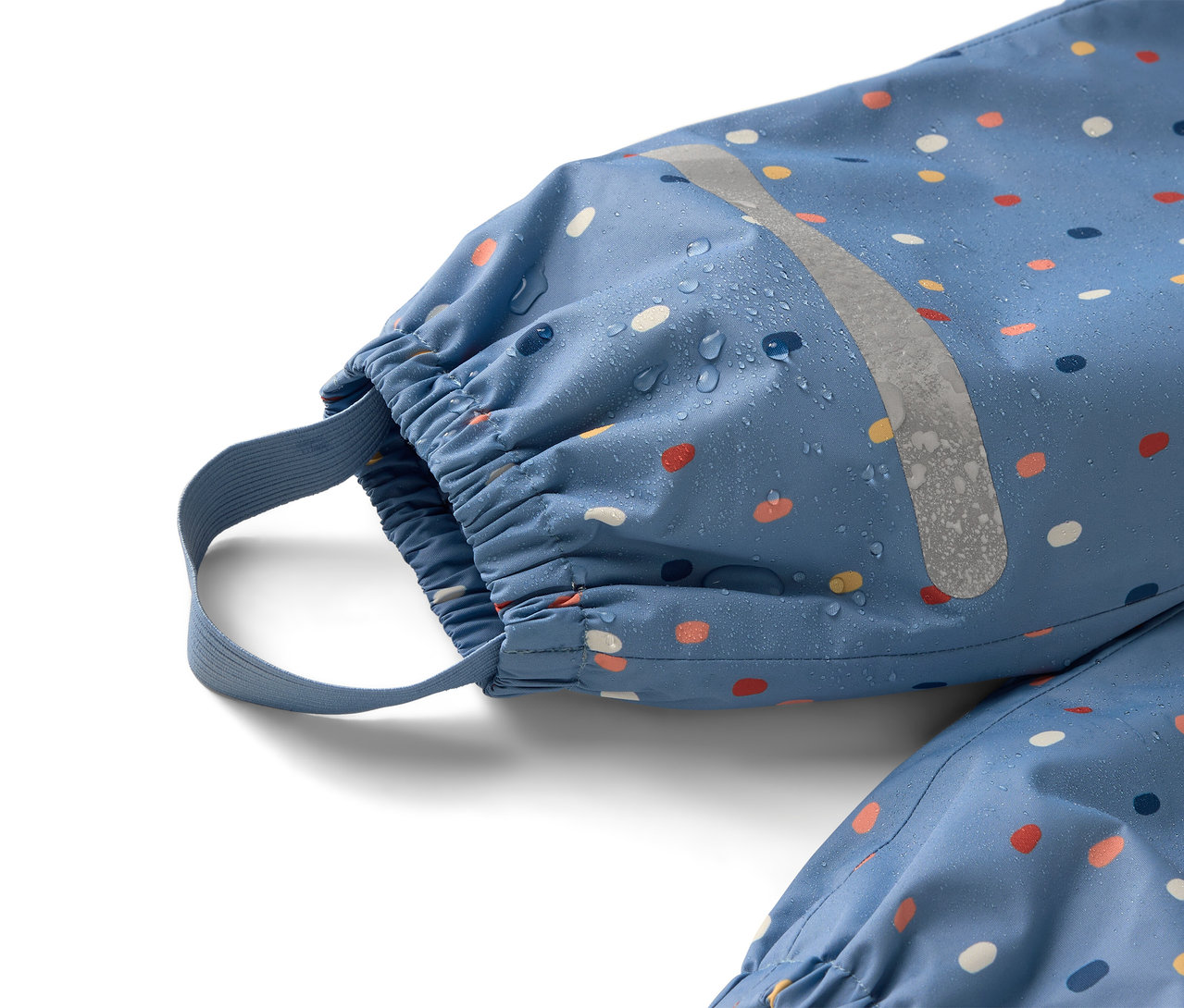 Gros plan sur une combinaison de pluie bleue à pois colorés avec une bande réfléchissante sur laquelle on peut voir des gouttes d'eau.