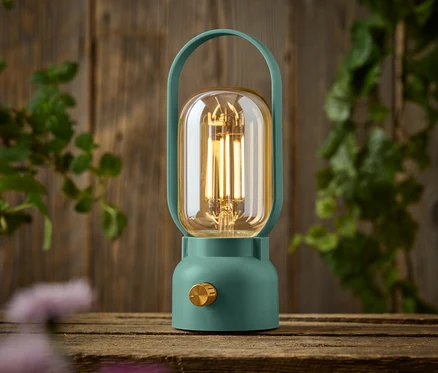Une lampe verte avec un bouton doré est posée sur une table en bois.