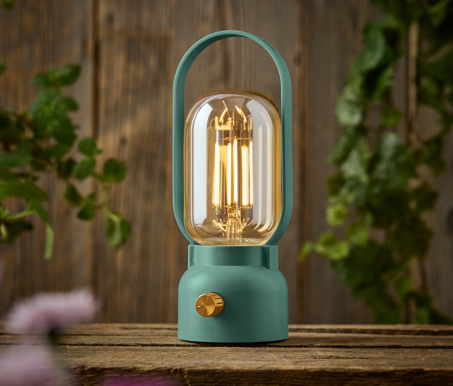 Une lampe verte avec un bouton doré est posée sur une table en bois.