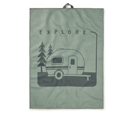 Une serviette vert clair avec une impression vert foncé d'une caravane entre deux arbres et le mot EXPLORE au-dessus.