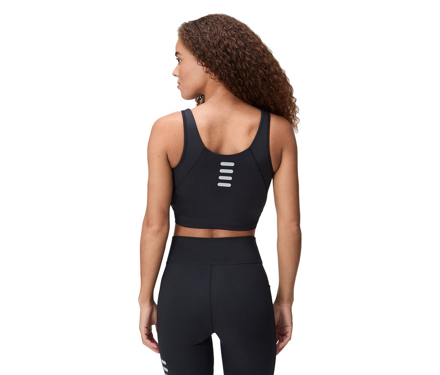 Femme portant un soutien-gorge de sport noir et un legging, vue de dos.