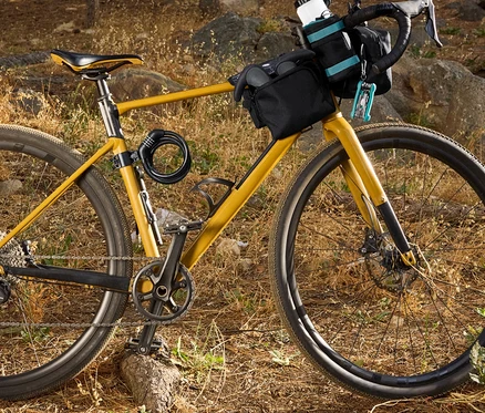 Vélo jaune avec sacoches noires et accessoires en forêt.