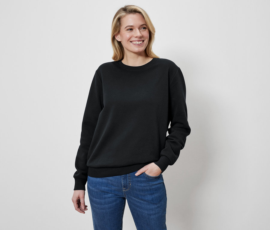 Femme blonde portant un pull noir et un jean.
