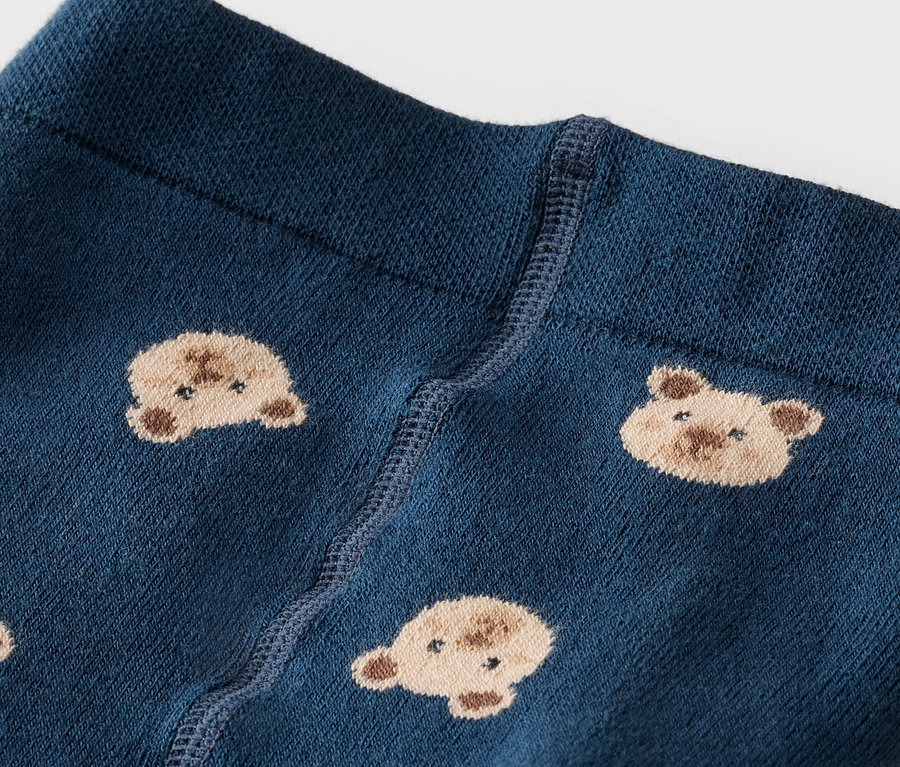 Gros plan de collants bleu marine avec une ceinture et un motif de visages d'ours en peluche.
