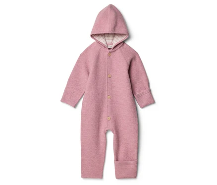 Une combinaison en laine rose avec capuche et boutons en bois sur fond blanc.