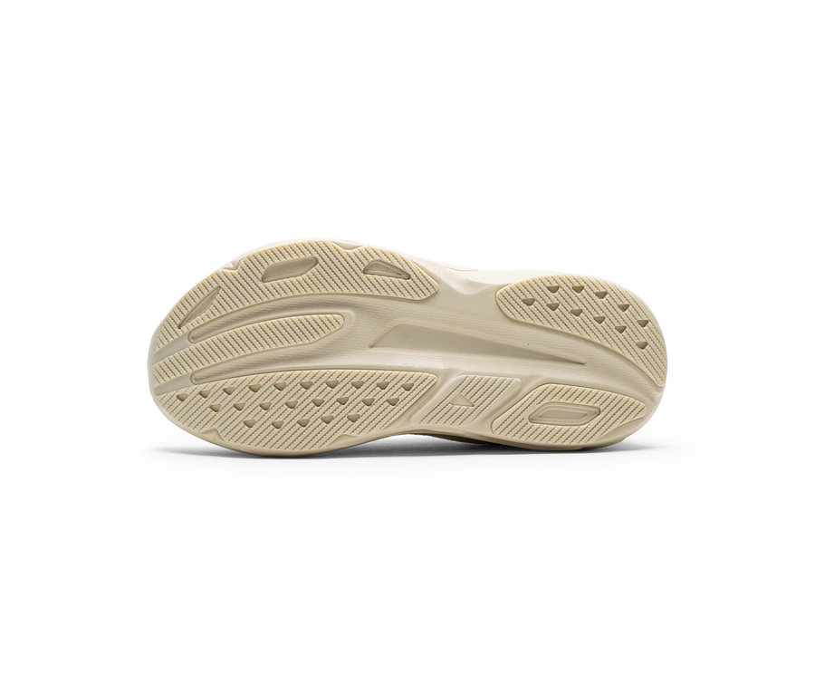 Semelle de chaussure beige avec un profil complexe de rainures et de picots triangulaires.