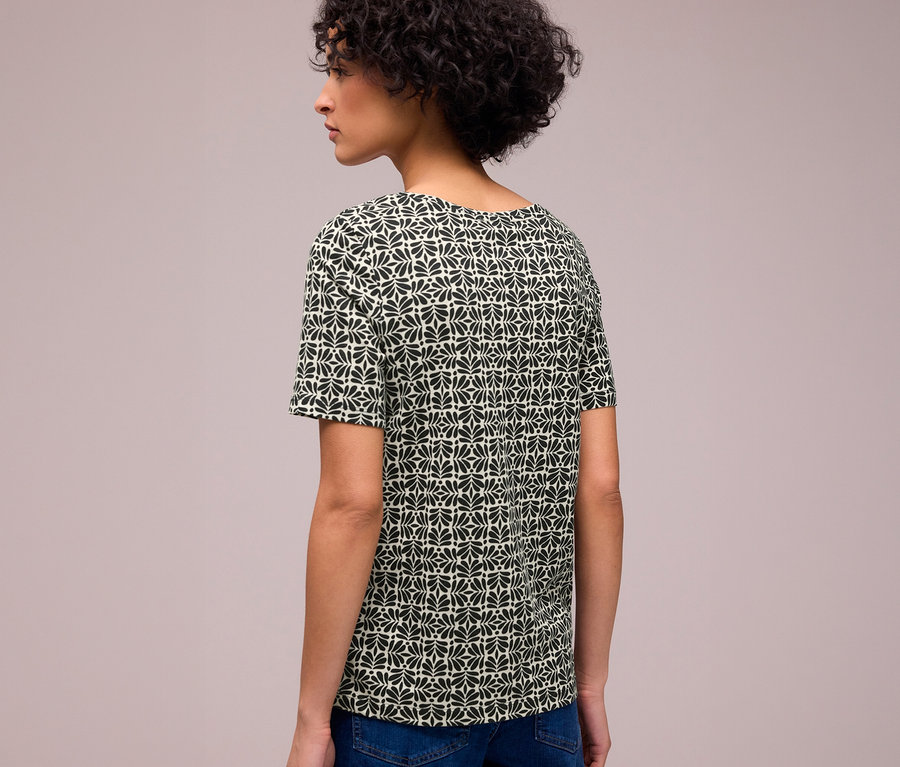 Femme de dos portant un T-shirt Street One à motif géométrique noir et vert clair.