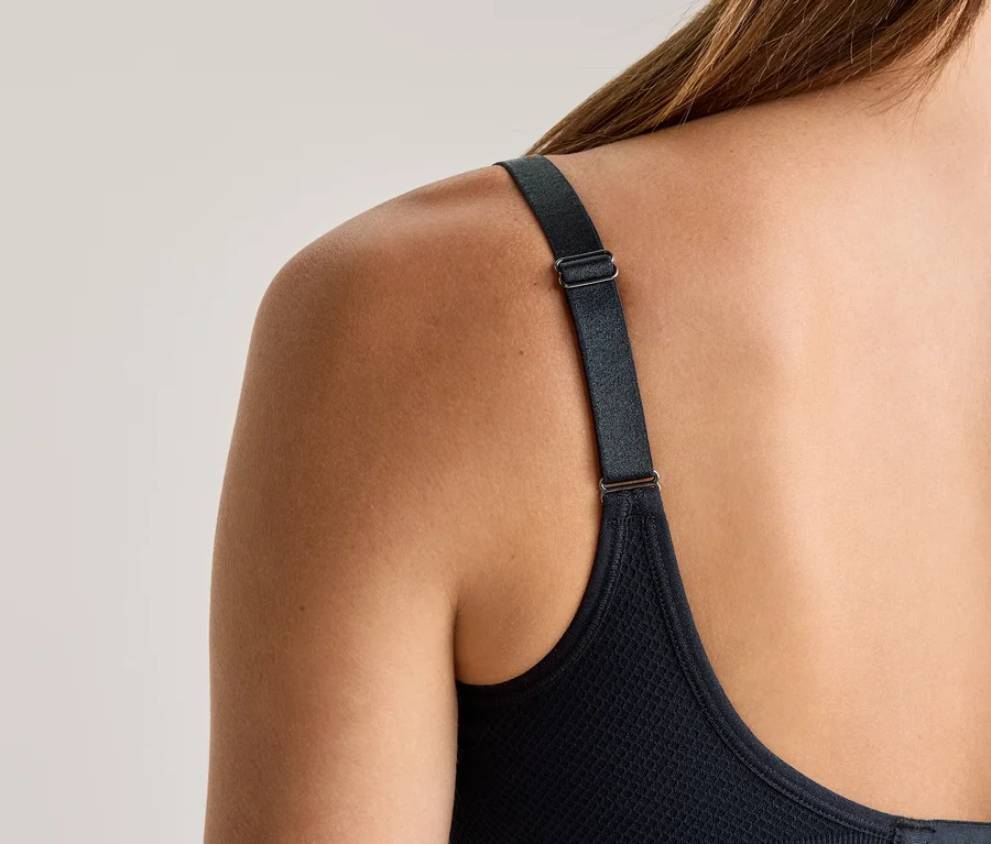 Vue de dos d'une femme aux cheveux longs portant un soutien-gorge foncé avec une bretelle réglable.