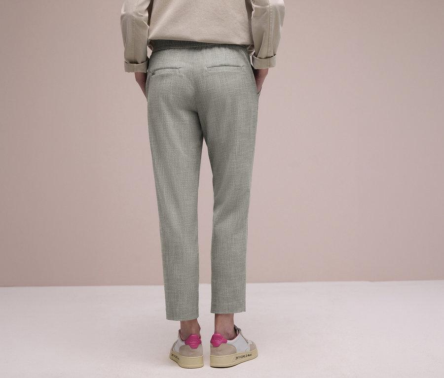 Personne de dos portant un pantalon de jogging Street One vert clair et des baskets beiges avec des touches de rose.