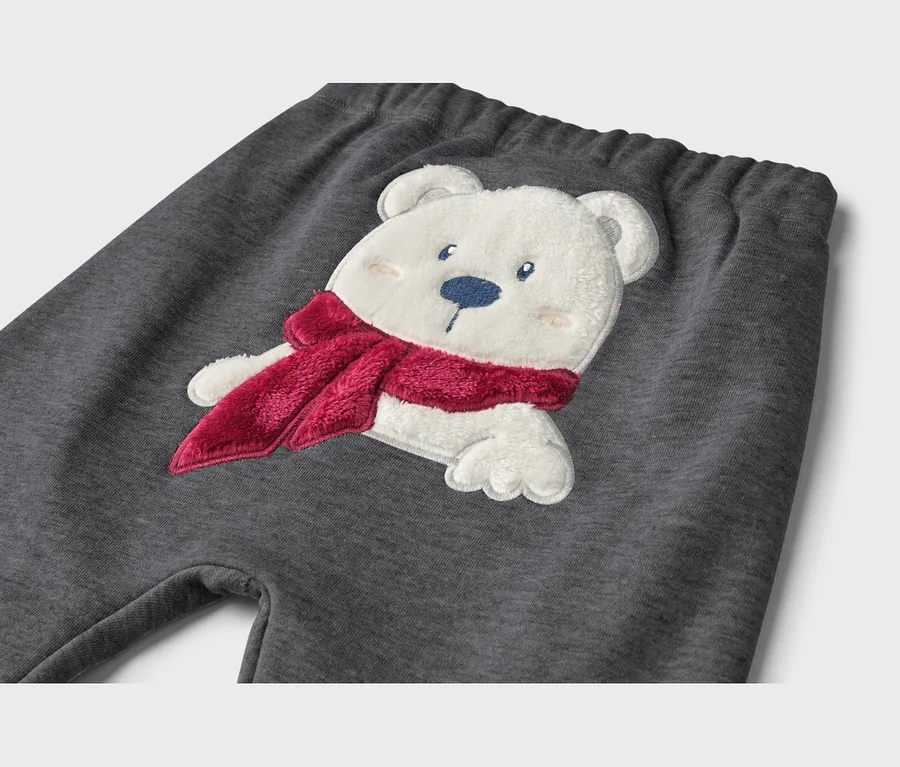 Pantalon de jogging gris foncé avec une application d'ours polaire blanc et moelleux portant une écharpe rouge.