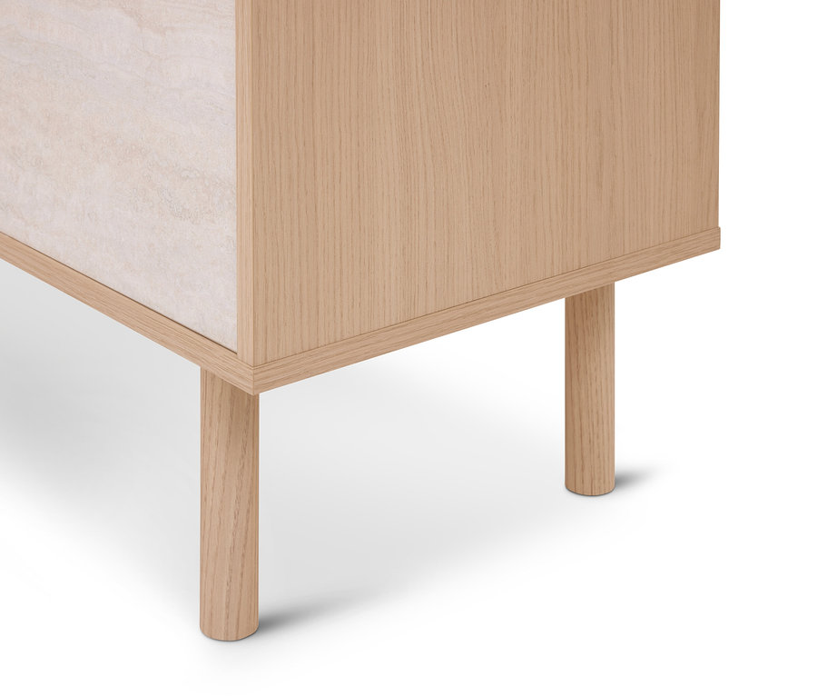 Coin inférieur d'une armoire en bois clair avec des pieds ronds en bois et un panneau latéral clair et texturé.