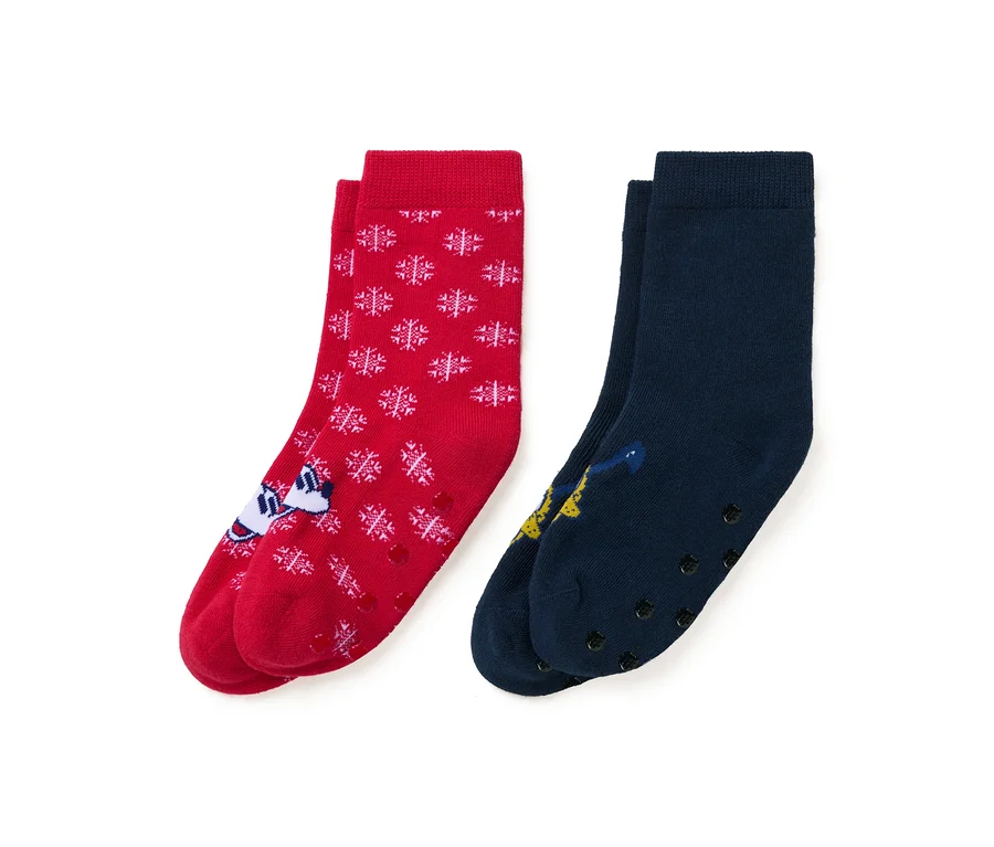 Deux paires de chaussettes : une rouge avec des flocons de neige blancs et un personnage de dessin animé, et une bleu marine avec un personnage de dessin animé.