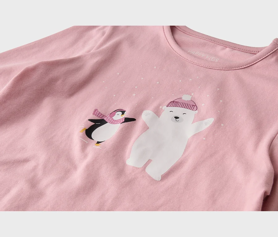 Haut rose à manches longues avec un motif de manchot patinant portant une écharpe rose et d'un ours polaire portant un bonnet rose, entourés de petites étoiles blanches. L'étiquette 'HAPPY KIDS' est visible à l'intérieur du col.