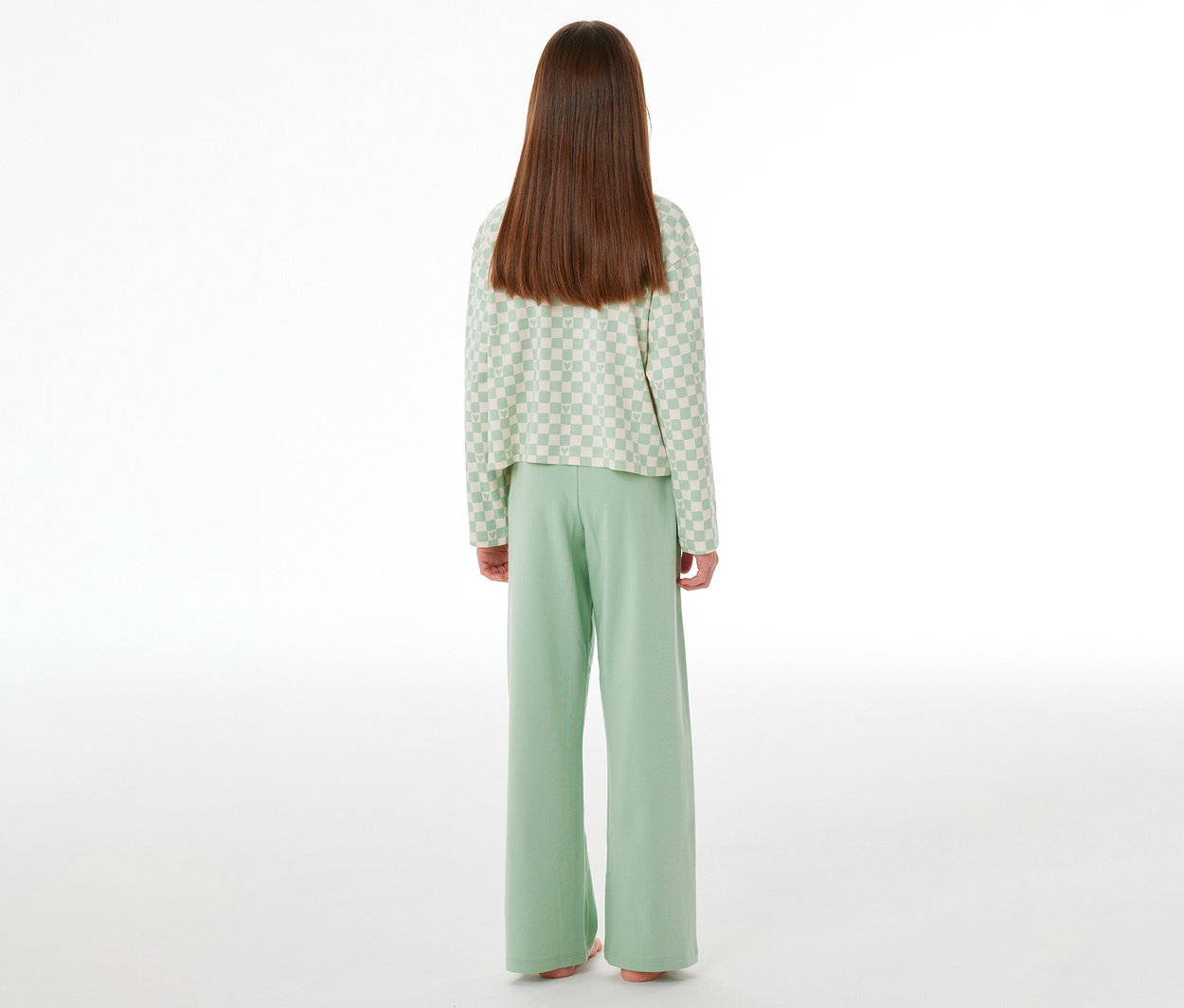 Enfant de dos portant un pyjama Interlock pour enfant SCHIESSER. Le haut à manches longues est à carreaux vert clair et blanc, et le pantalon est vert clair uni.