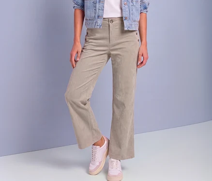 Une personne porte un pantalon en velours côtelé Street One beige clair à jambes larges avec des boutons décoratifs, une veste en jean et des baskets roses et blanches.