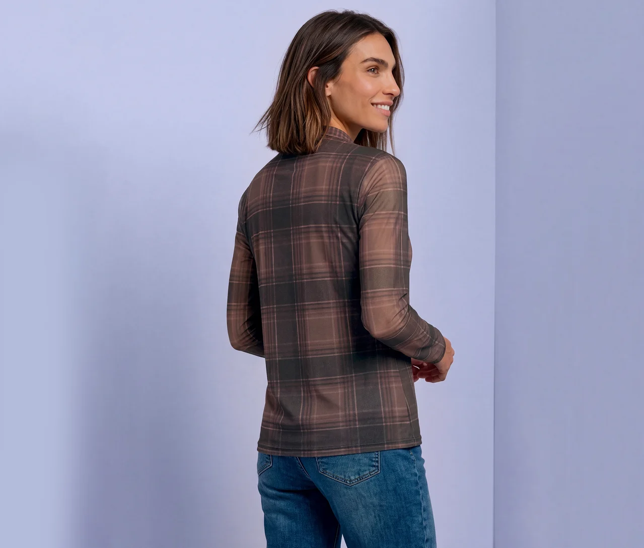 Femme aux cheveux bruns courts, portant un T-shirt en maille Street One à carreaux marron et un jean, regardant par-dessus son épaule.