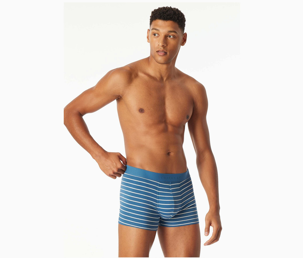 Un homme torse nu ajuste son caleçon boxer bleu à rayures blanches.