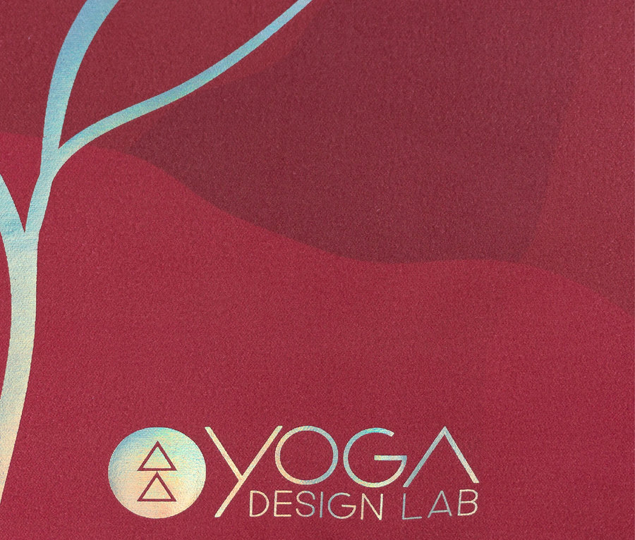 Gros plan d'un tapis de yoga rouge avec le logo Yoga Design Lab et un motif bleu.
