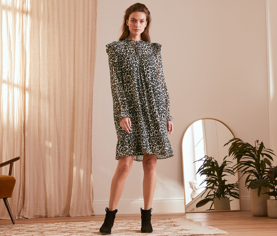 Femme posant dans une robe à imprimé intégral et des bottes noires.