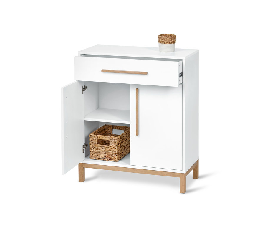 Meuble de salle de bain blanc avec tiroir ouvert et porte, à l'intérieur un panier en osier.