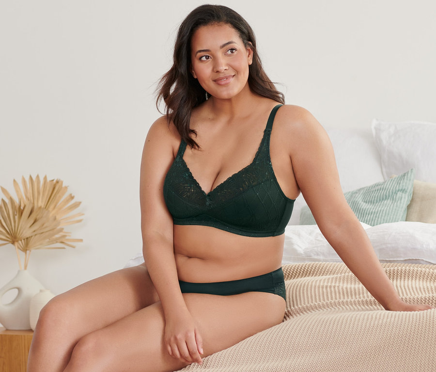 Femme assise sur un lit portant un soutien-gorge doux.