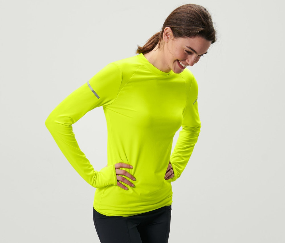 Femme posant en T-shirt fonctionnel manches longues jaune fluo.