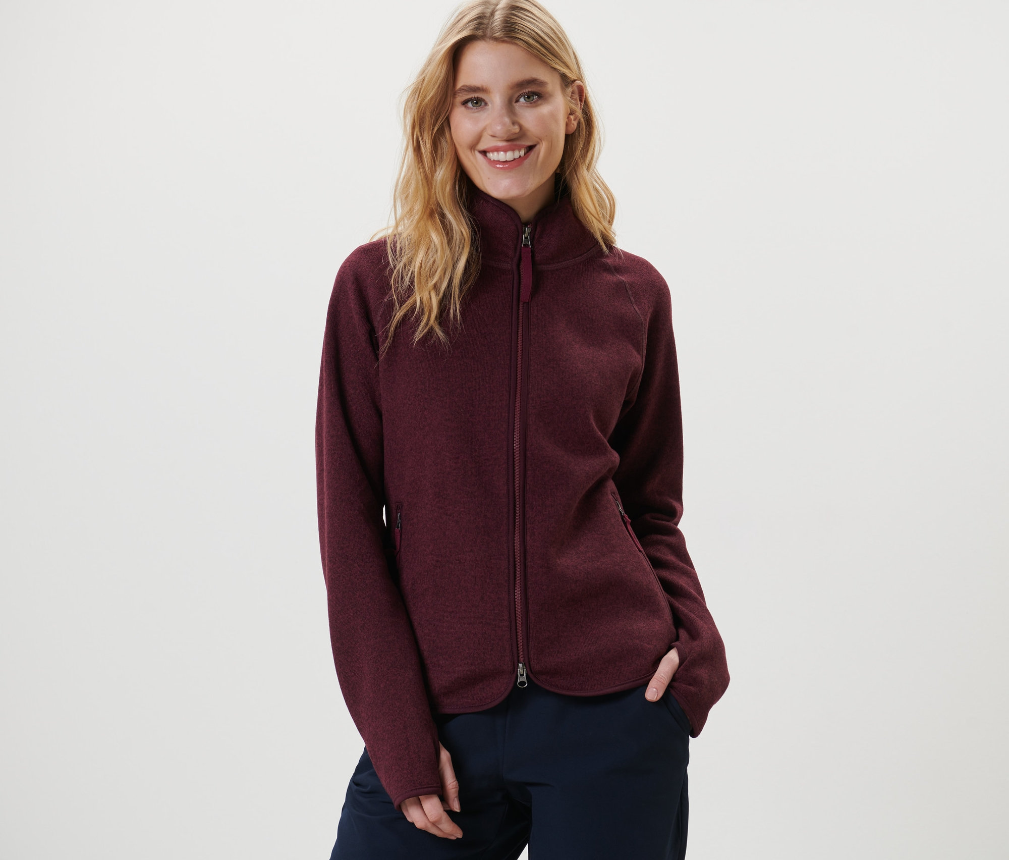 Une femme porte une veste en maille polaire bordeaux.
