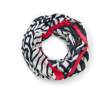 Un foulard loop imprimé en noir, blanc et rouge est posé sur un fond blanc.