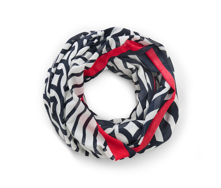 Un foulard loop imprimé en noir, blanc et rouge est posé sur un fond blanc.