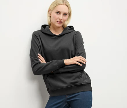 Femme blonde posant dans un sweat à capuche anthracite.