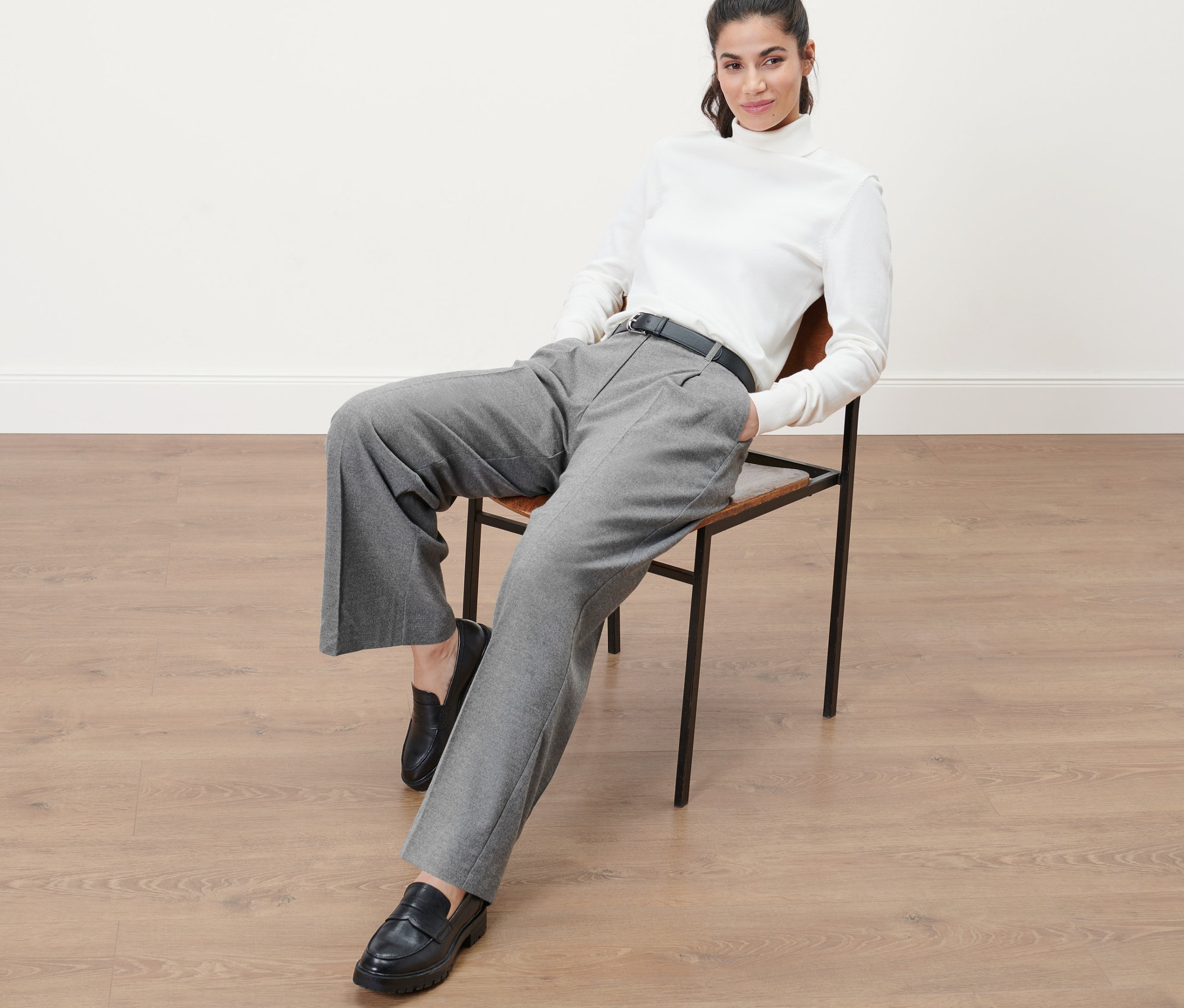 Femme assise sur une chaise portant un pantalon tissé.