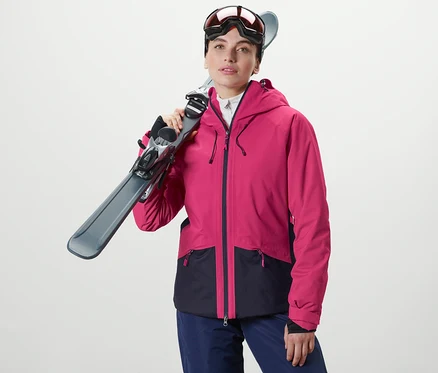 Femme tenant des skis sur son épaule. Elle porte une veste de ski.