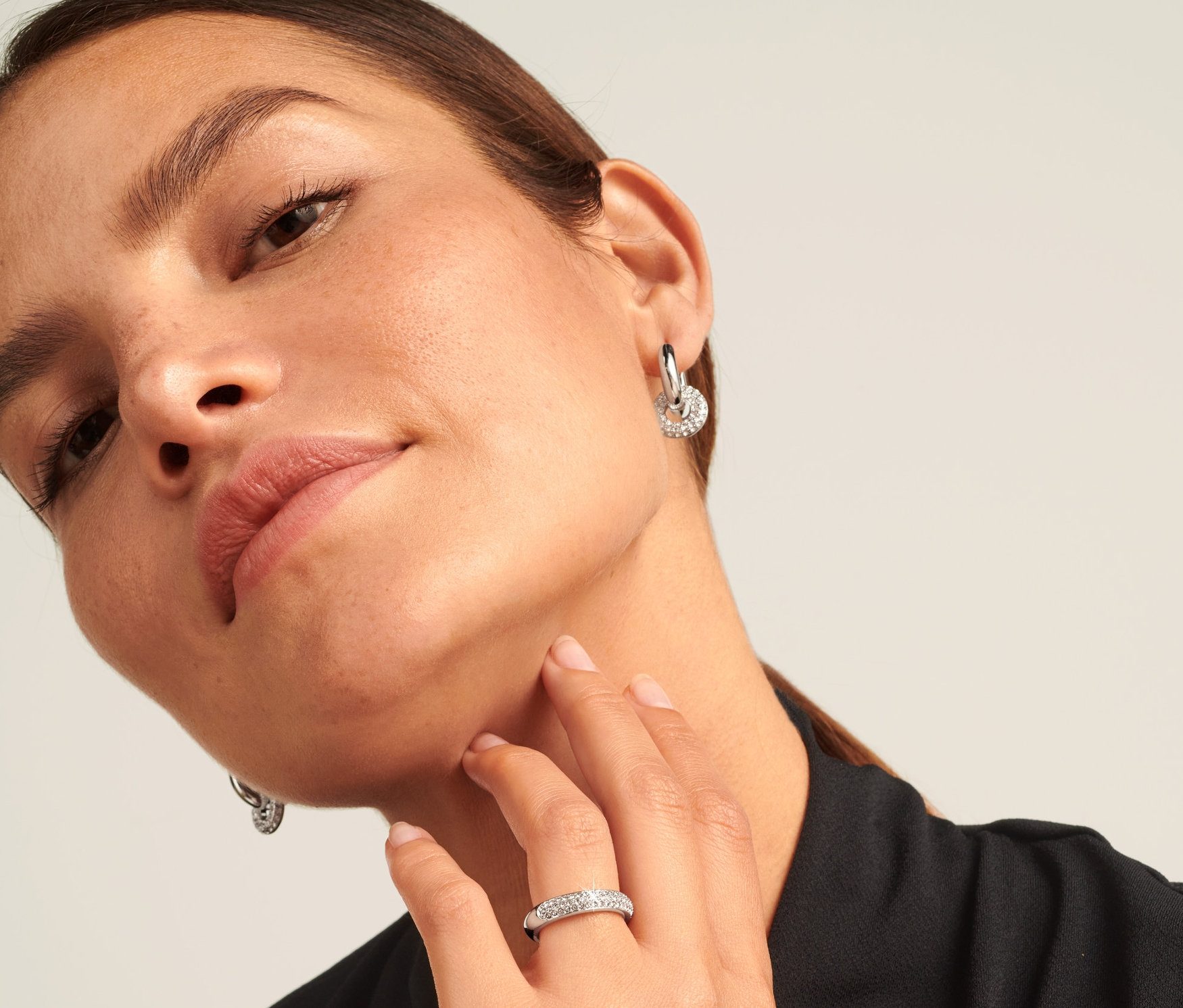 Femme portant une bague argentée Sparkle Donut à l'annulaire et des boucles d'oreilles.