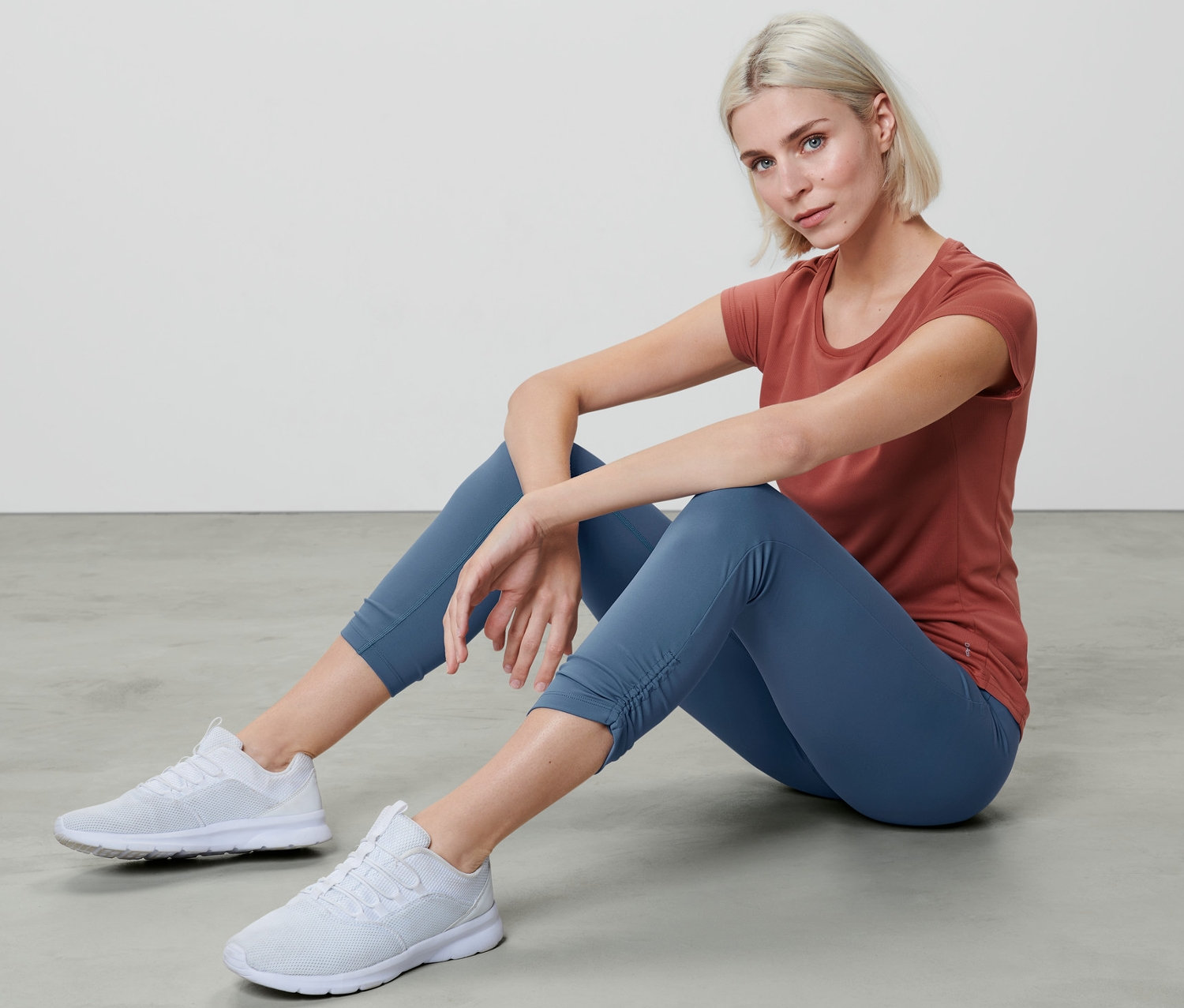 Femme assise par terre portant un collant de sport 7/8 et un t-shirt.