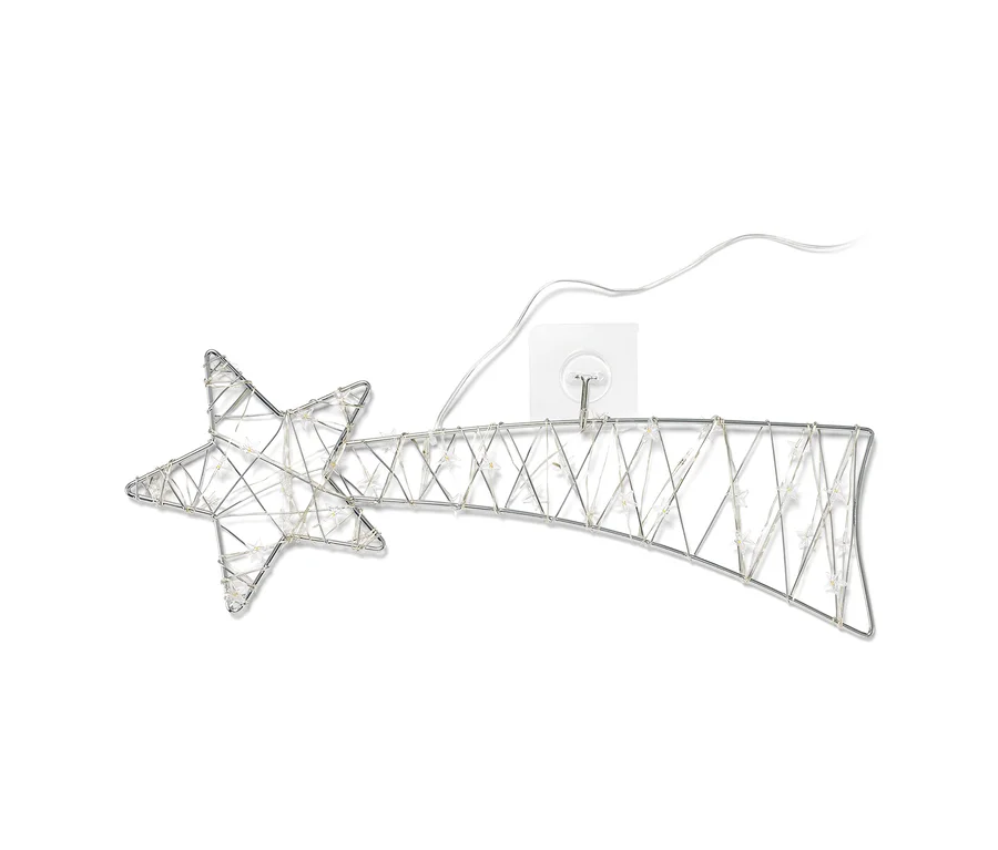 Une petite étoile filante LED argentée accrochée à un mur blanc.