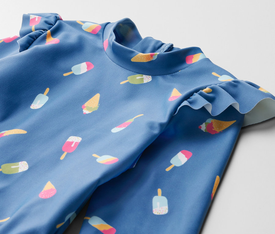 Gros plan sur un maillot de bain bleu pour enfant avec imprimé de glaces et protection UV 80.
