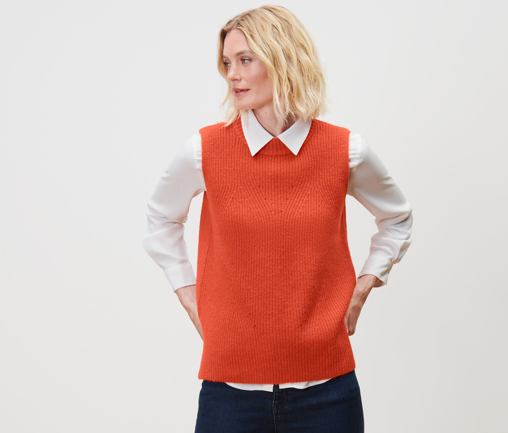 Une femme portant un pull sans manches en maille orange.